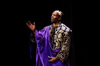 An actor performing a monologue in crown and purple cape