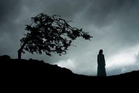 An atmospheric image of a mystery woman in a dress, wondering the moor, on a stormy night.