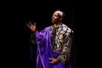 Actor dressed as a king in purple and gold robes and headdress
